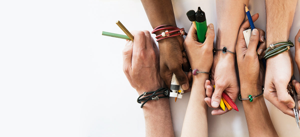 6 Hände, wobei jedes Handgelenk ein Trollbeads-Armband und Perlen enthält